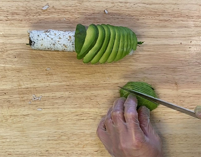 Thinly slice avocados and top it on the roll 