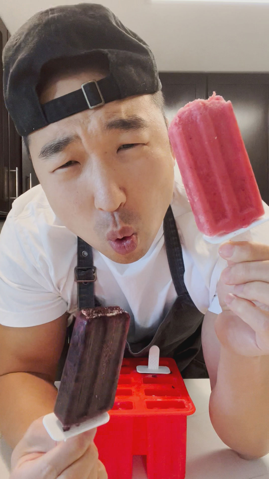Chef Chris Cho holding strawberry and blueberry fruit popsicles