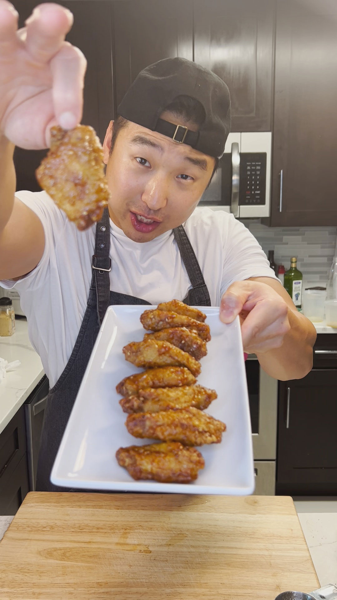 Chef Chris Cho holding a plate of honey garlic chicken wings 