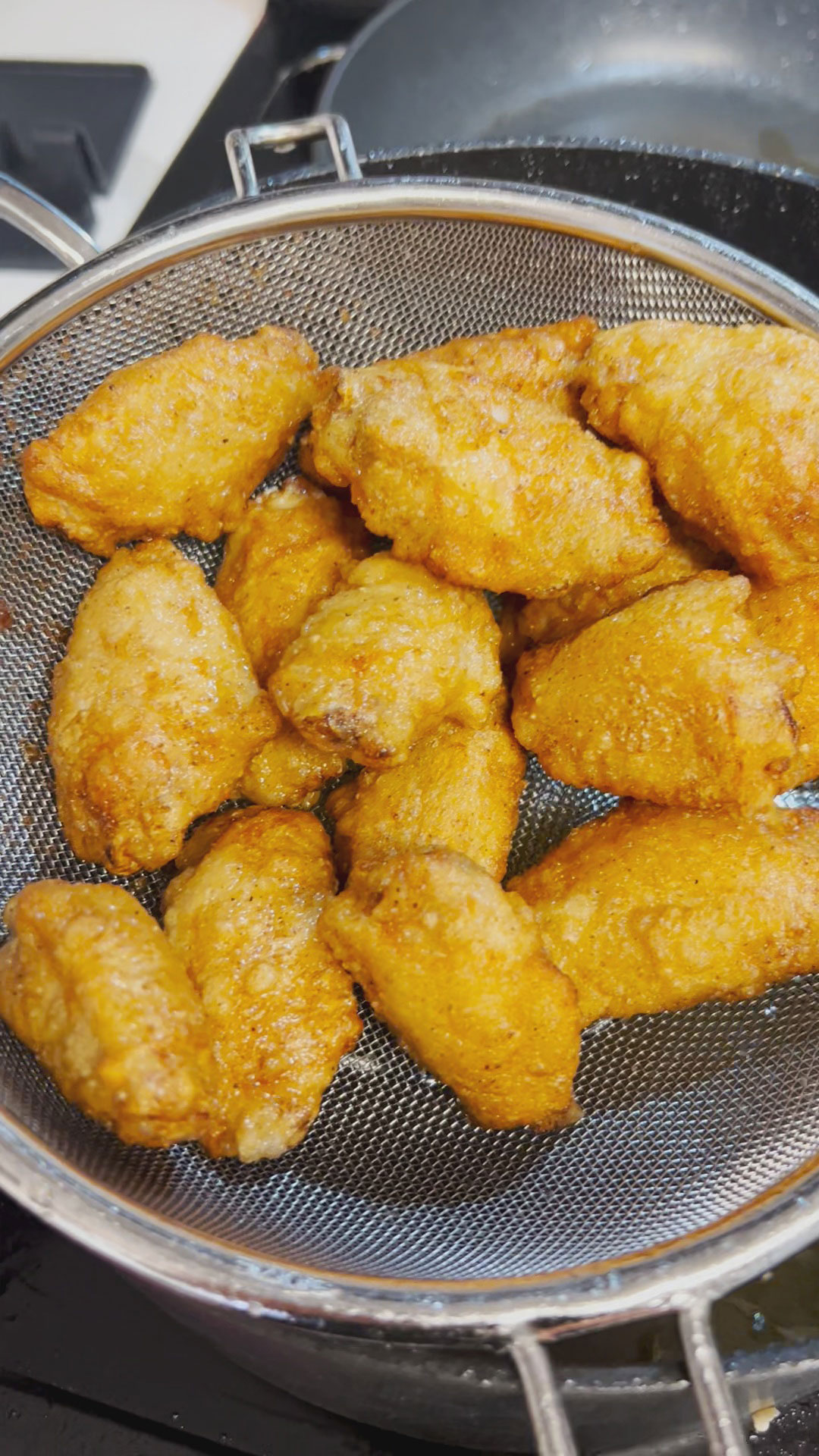 Crispy fried chicken wings in a strainer 