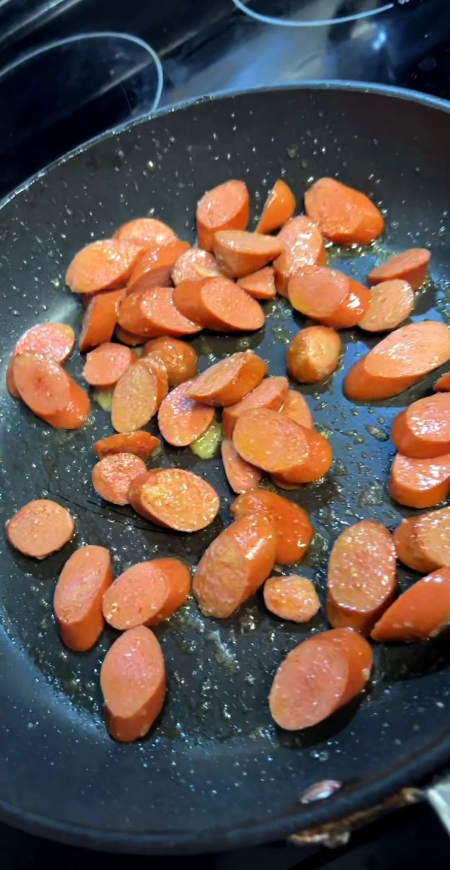 Hotdogs being stir fried in a pan 