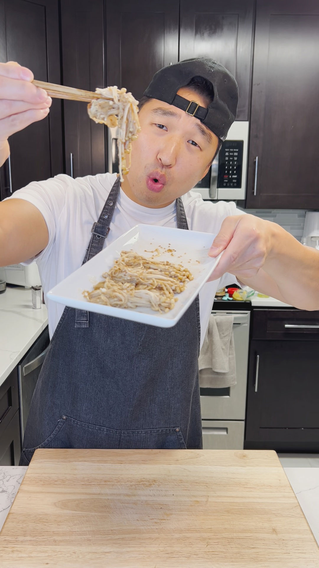 Chef Chris Cho holding a plate of soy garlic enoki mushroom