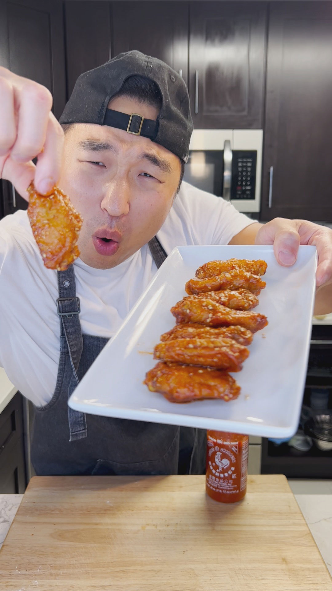 Chef Chris Cho holding a plate of sriracha chicken wings 