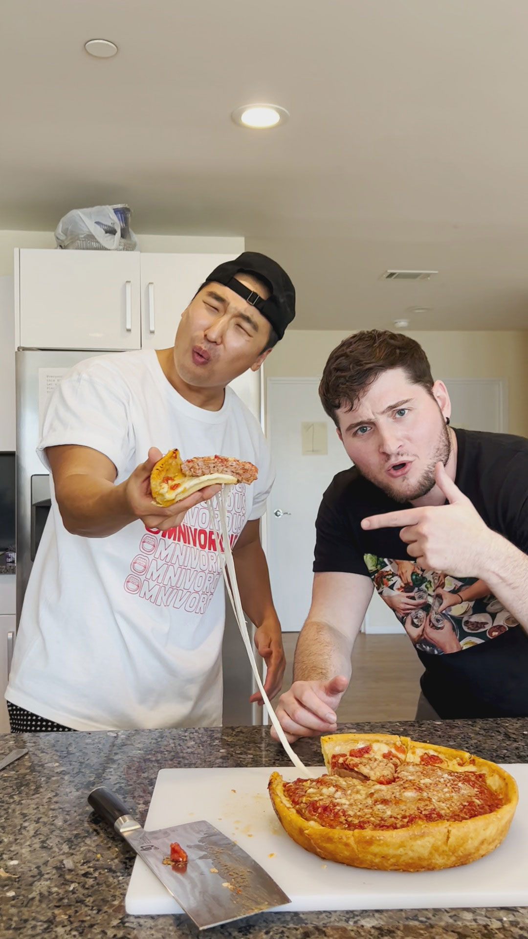 Chef Chris Cho and Omnivorous Adam with a deep dish pizza cheese pull 