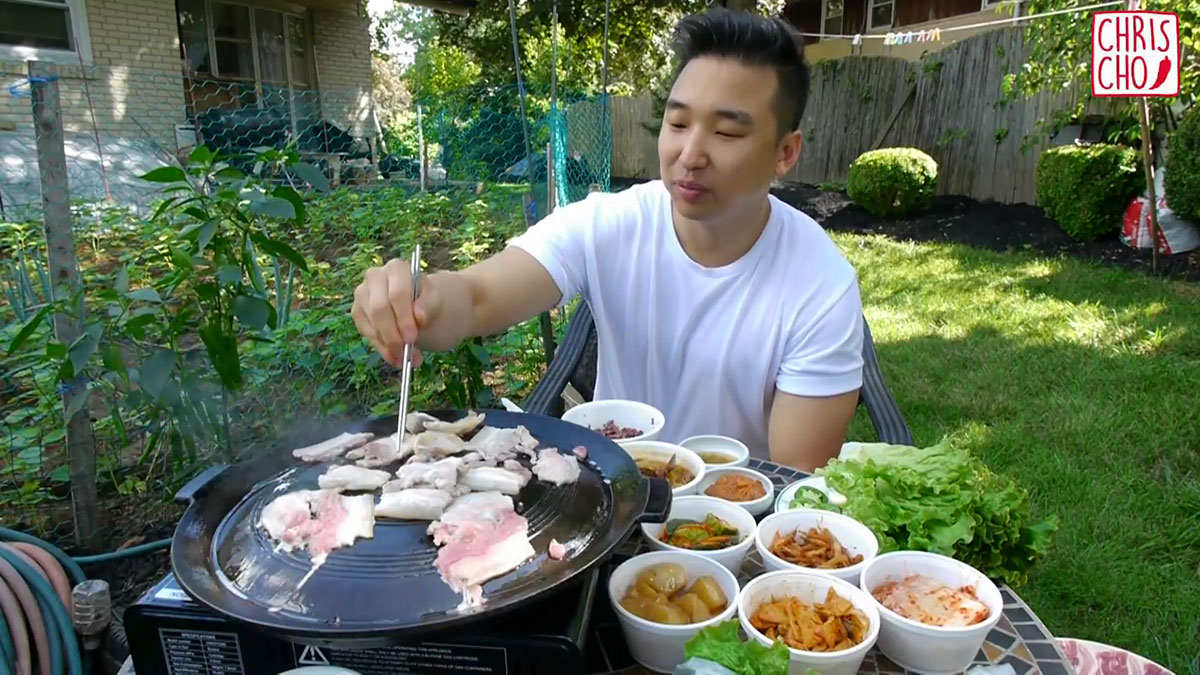 Chef Chris Cho doing Korean BBQ outdoors with a portable stove and grill pan 