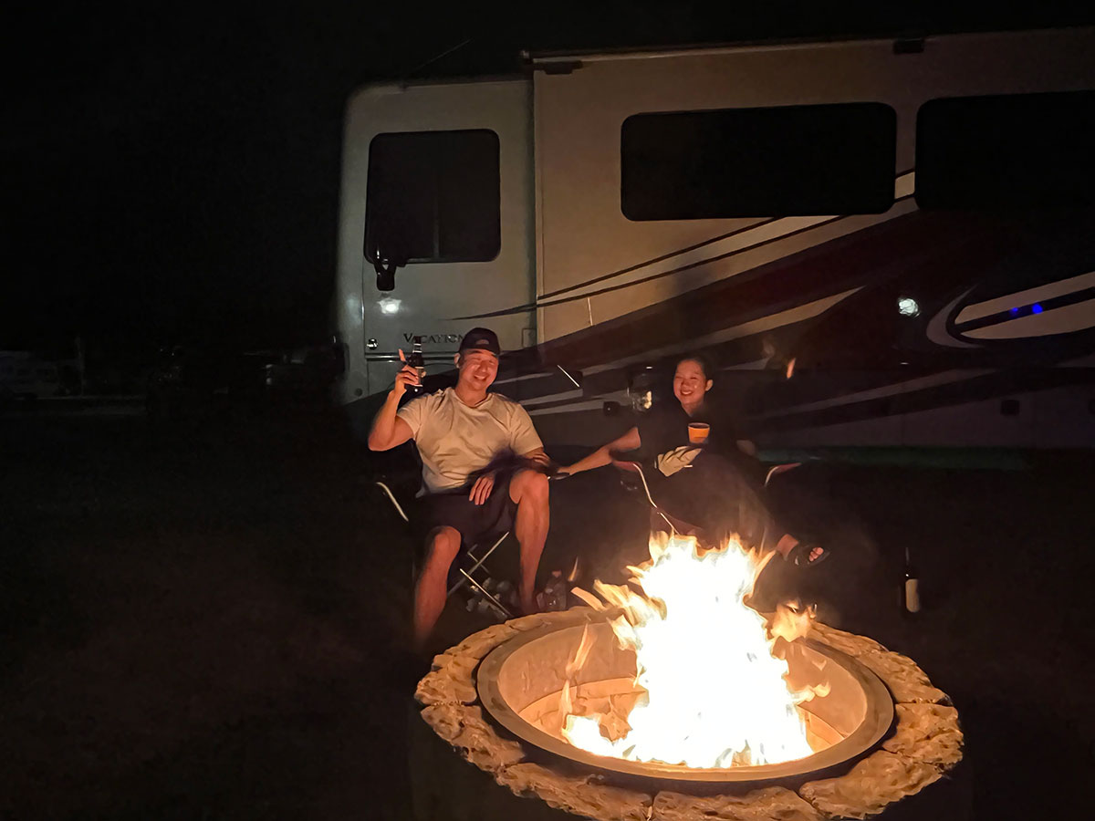 Chef Chris Cho and wife sitting in front of a bonfire 