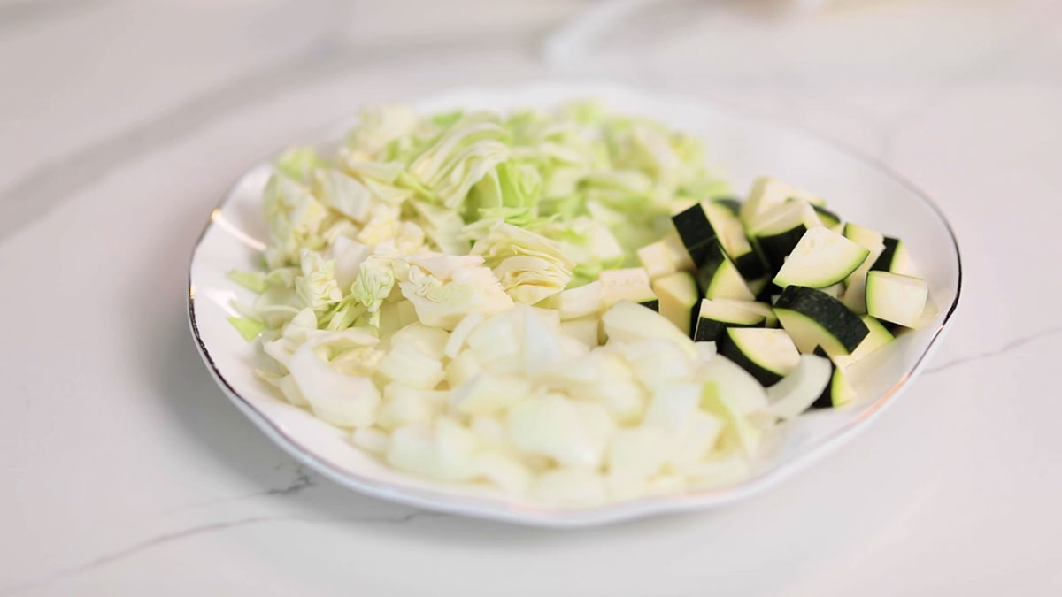 Plate of chopped cabbage, zucchini, and onion 