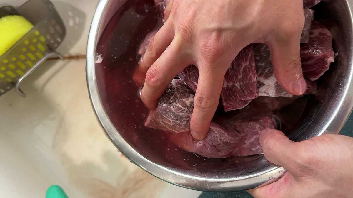 Removing the "pin mool" or iron from the meat by soaking it in water 