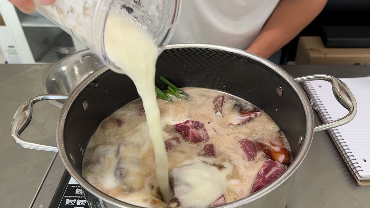 Combining short ribs, sauce ingredients, and blended aromatics in a pot