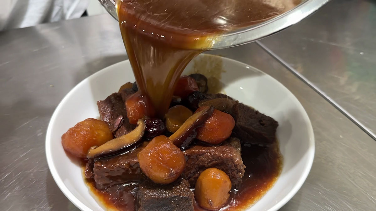 Pouring the sauce back into the plated short ribs 