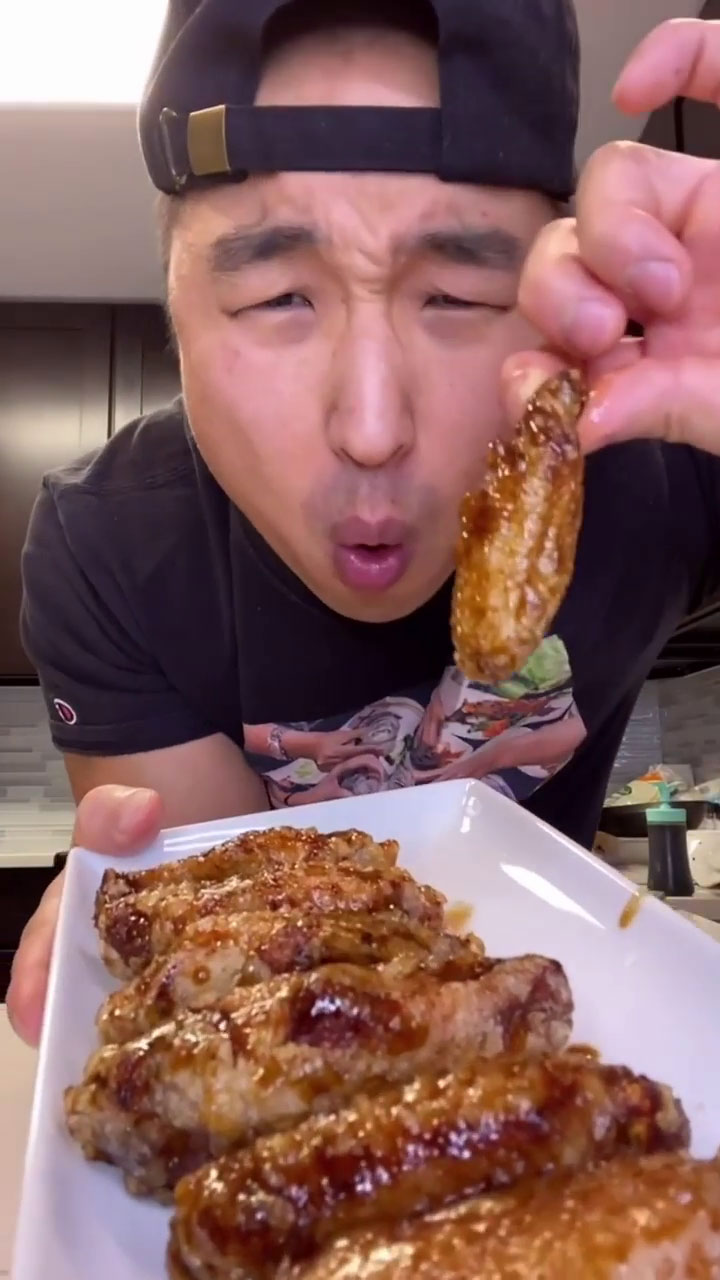 Chef Chris Cho holding a plate of soy garlic chicken wings 