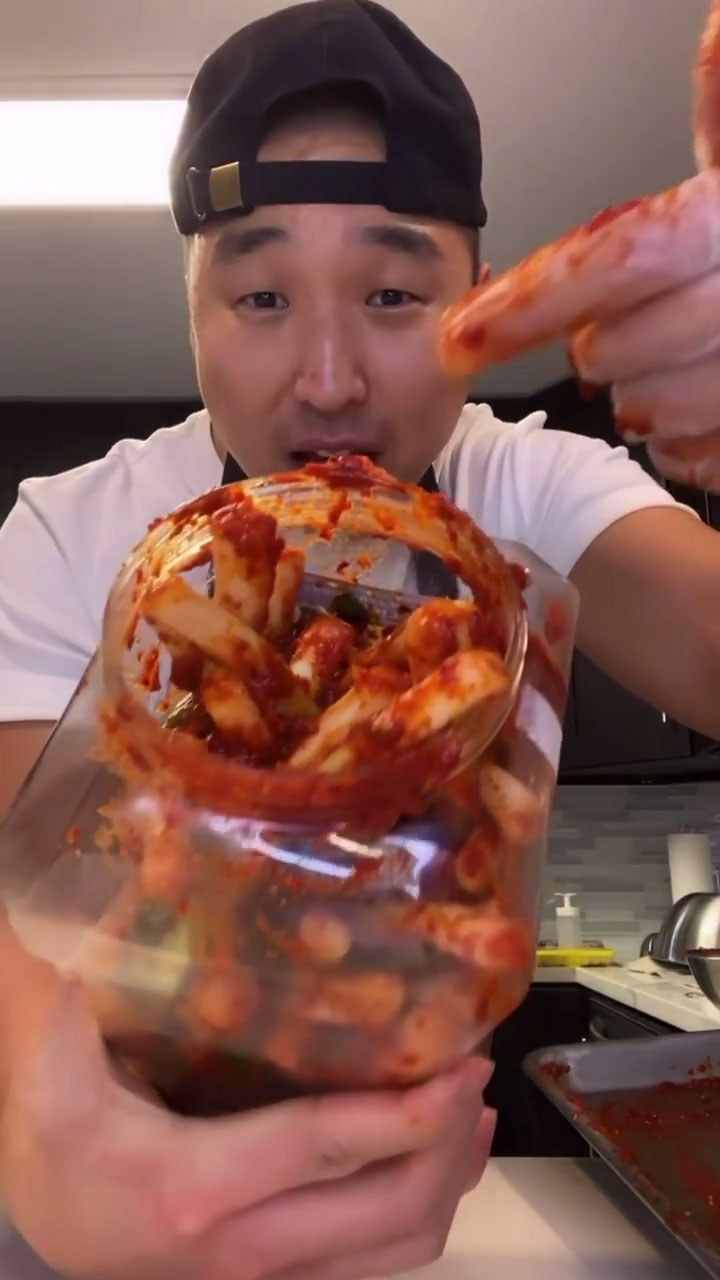 Placing green onion kimchi inside a kimchi container 