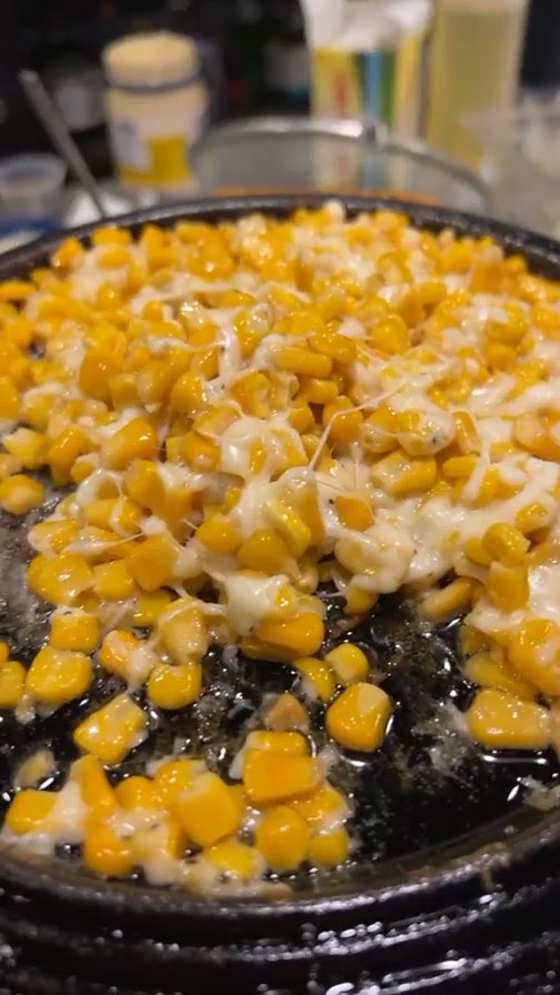 Place corn in a sizzling pan and top with cheese