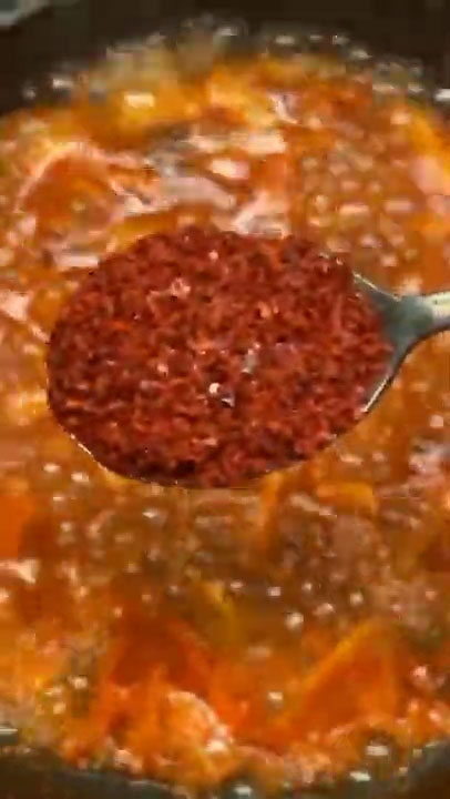 Season the boiling kimchi with garlic, soy sauce, and gochugaru