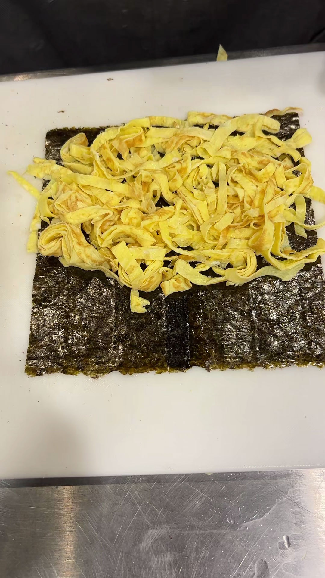 Lay seaweed paper flat and place egg strips on top