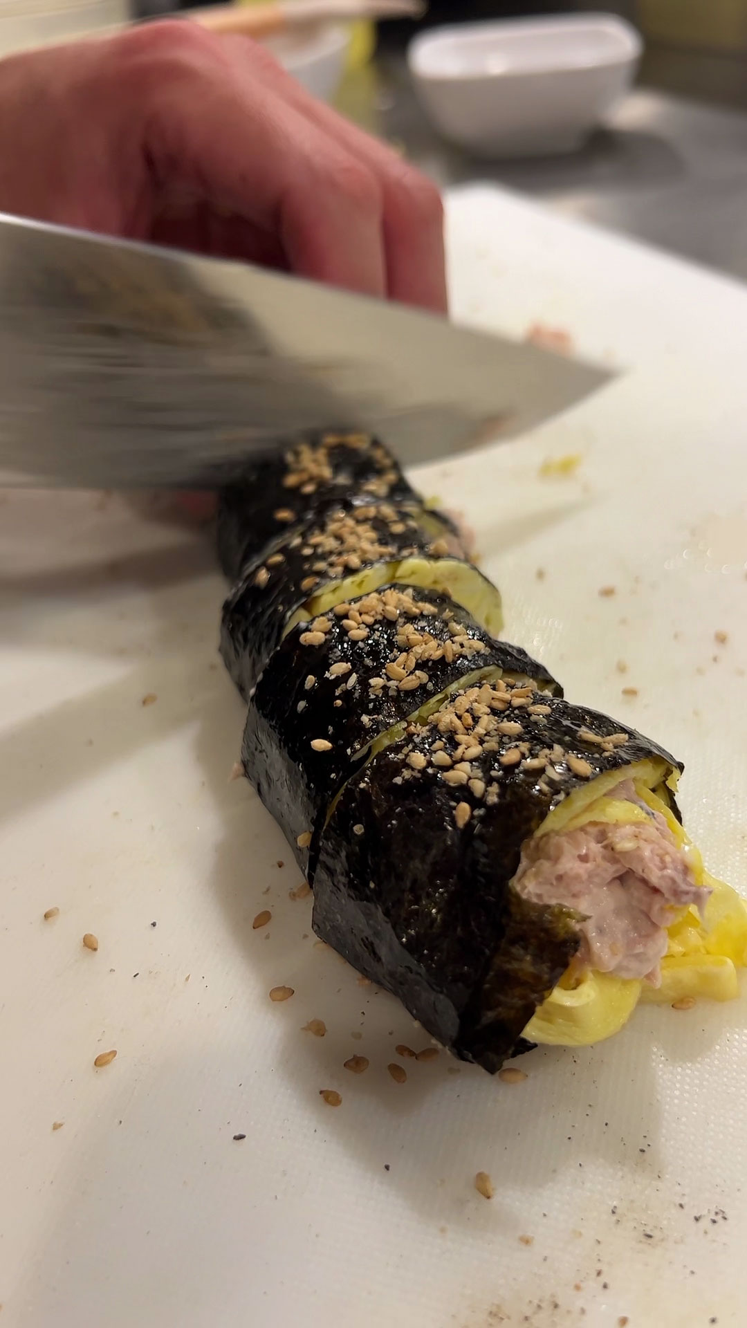 Garnish kimbap with sesame oil and sesame seeds, then slice