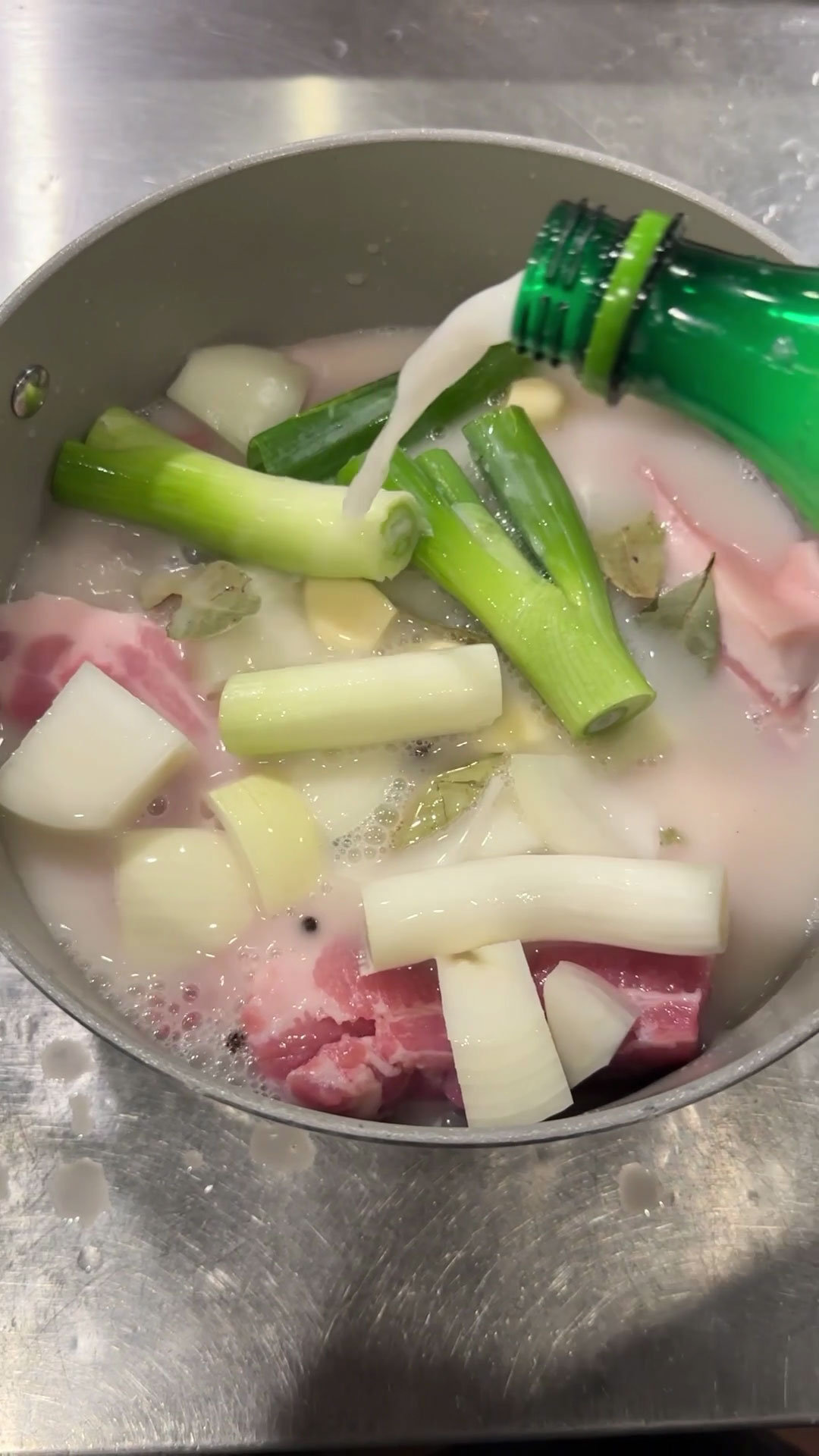 Pour makgeolli and soy sauce over the pork belly and aromatics 