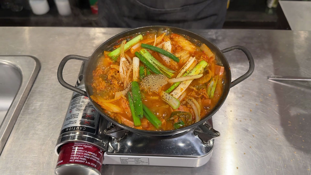 Add onion and scallions, then season with garlic, hondashi, and black pepper